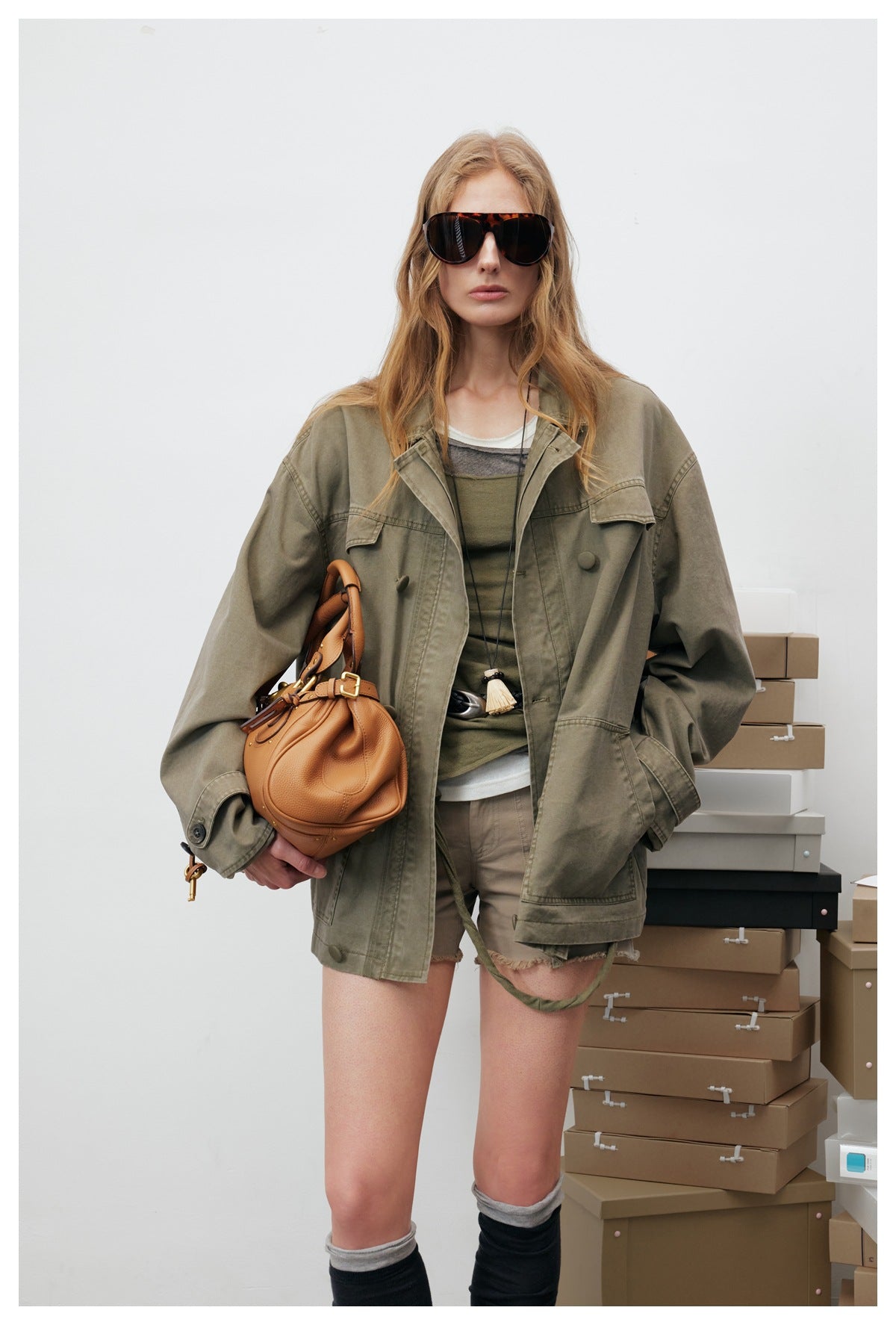Model wearing an oversized olive utility jacket with flap chest pockets, large lower pockets and a button front.