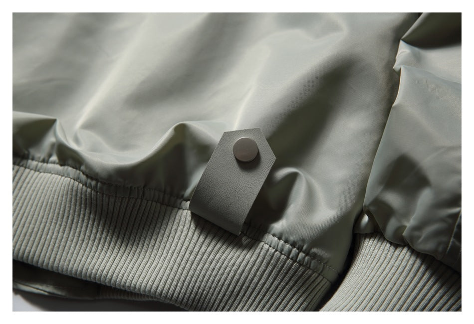 Close-up of the light gray jacket's ribbed hem and a snap-fastened tab.
