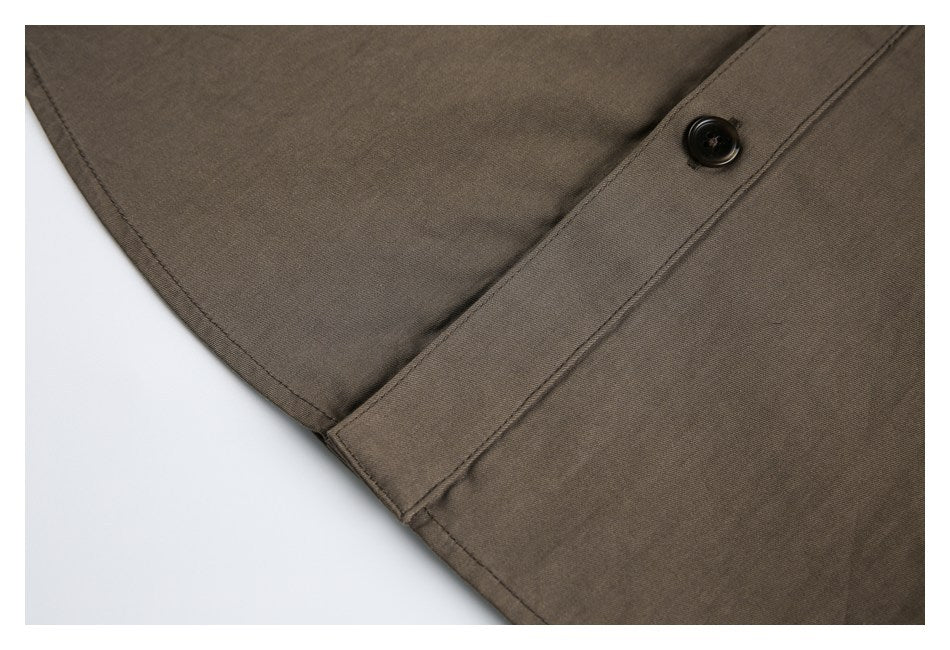 Close-up of brown garment fabric with a stitched edge and a single dark button.