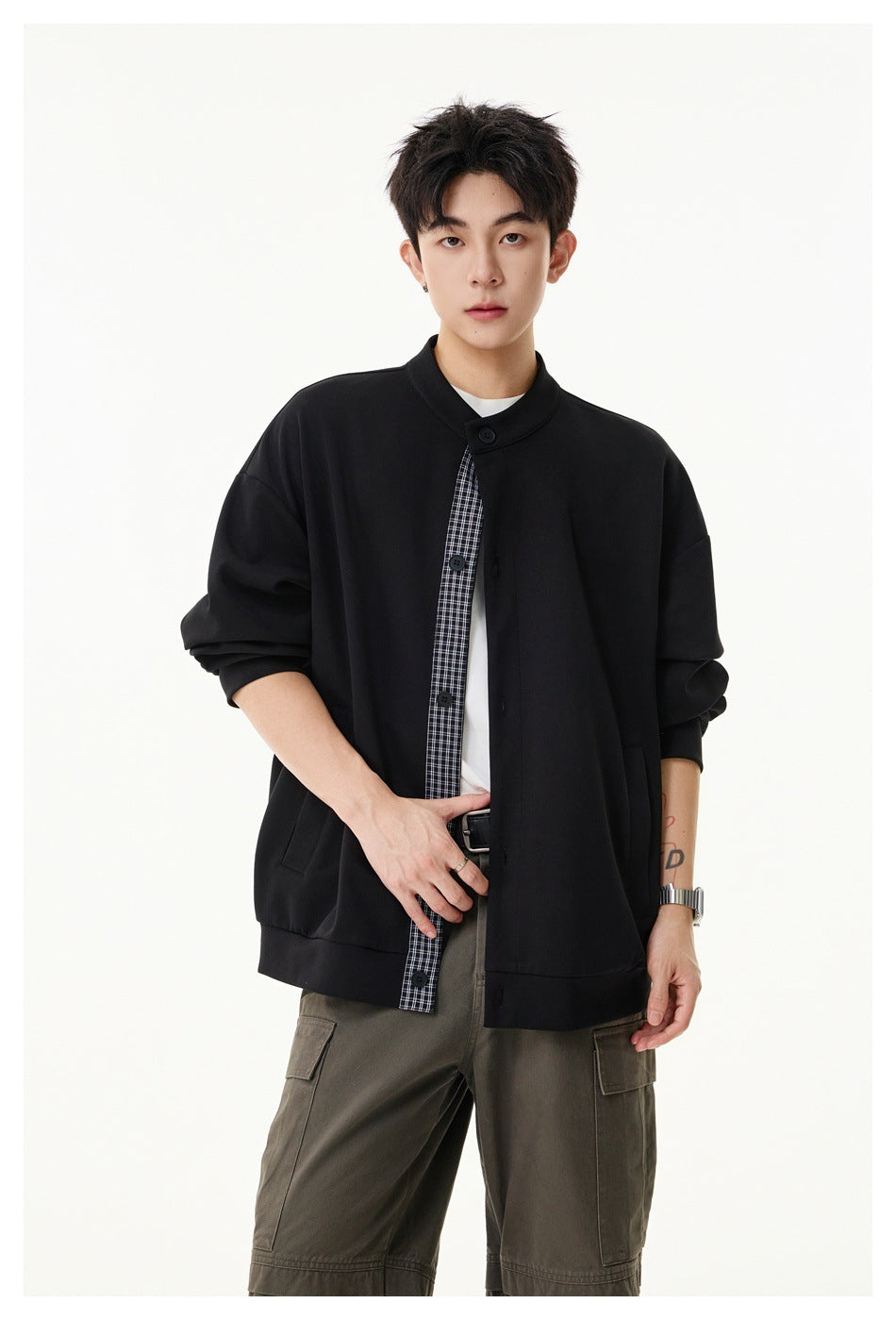Model wears an open black stand-collar jacket with a checked placket, white shirt, and olive cargo trousers.