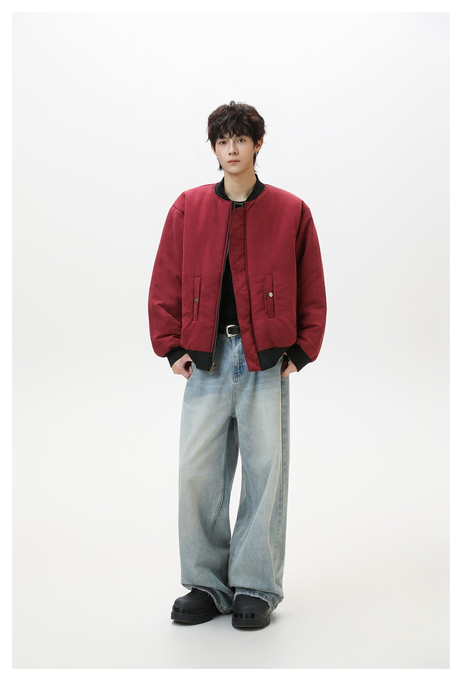 Full-length front view of a model wearing a burgundy bomber jacket with black trim and snap pockets.