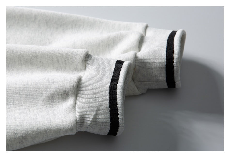 Close-up of light gray heather sleeves with ribbed cuffs edged by black stripes.
