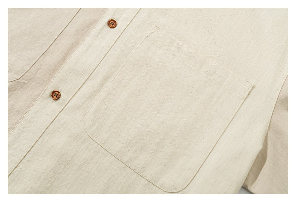 Close-up of a cream garment showing a large stitched patch pocket and two brown buttons.
