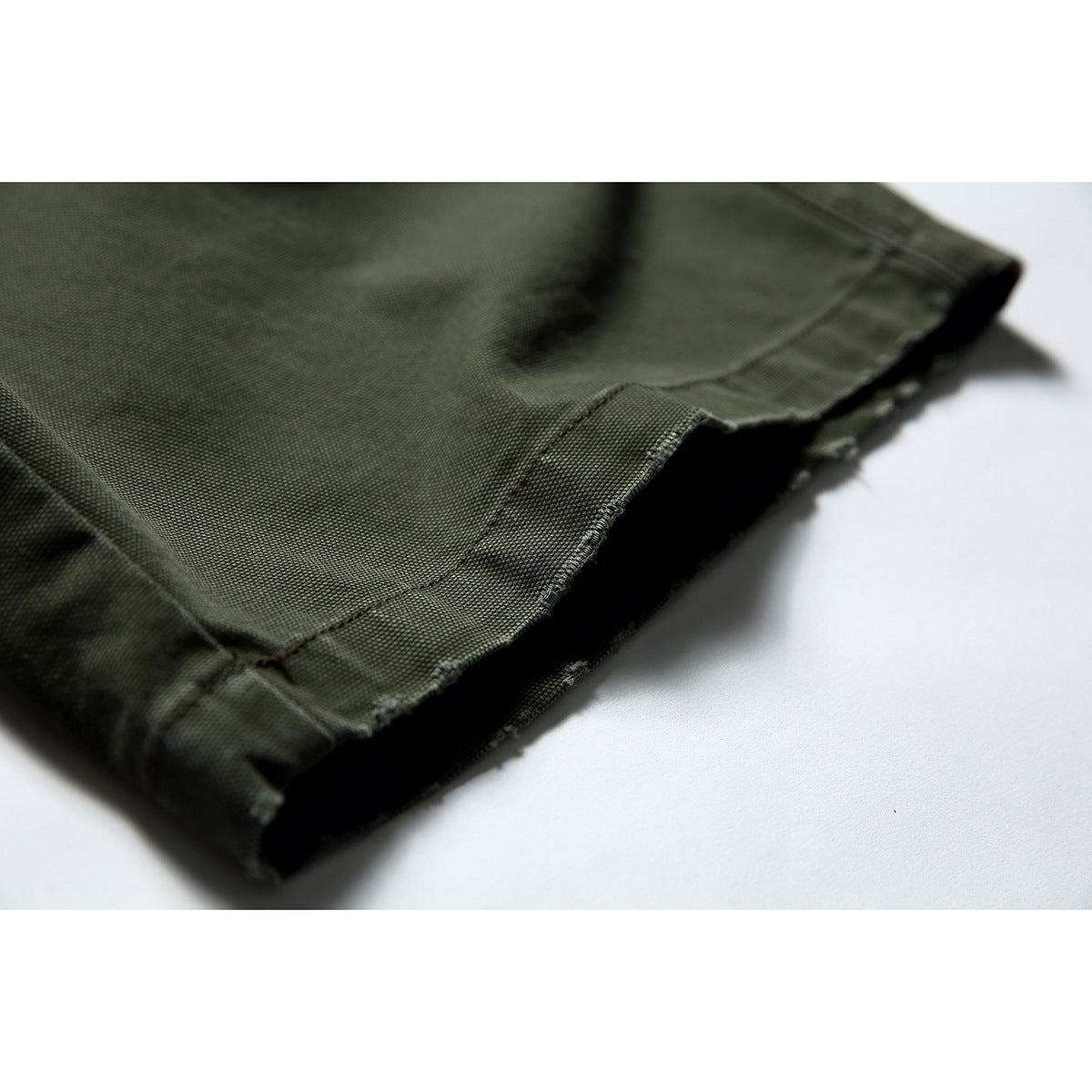 Close-up of the olive shorts' hem, showing the folded edge and stitching.