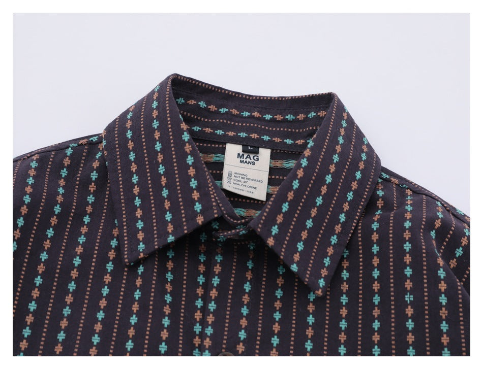 Close-up of the shirt collar and sewn neck label on a dark shirt with turquoise and rust motifs.