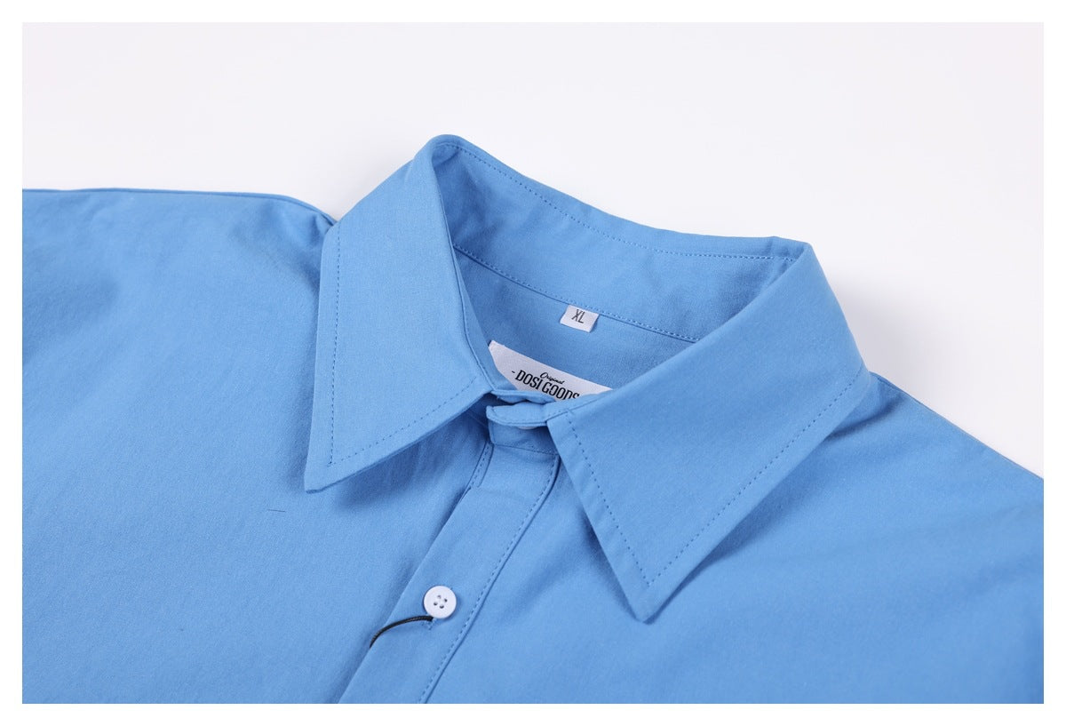 Close-up of a light blue shirt collar, white button, and inner neck labels.