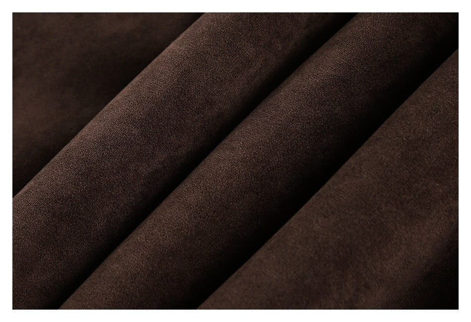 Macro view of dark brown fabric arranged in soft folds, showing its fine surface texture.