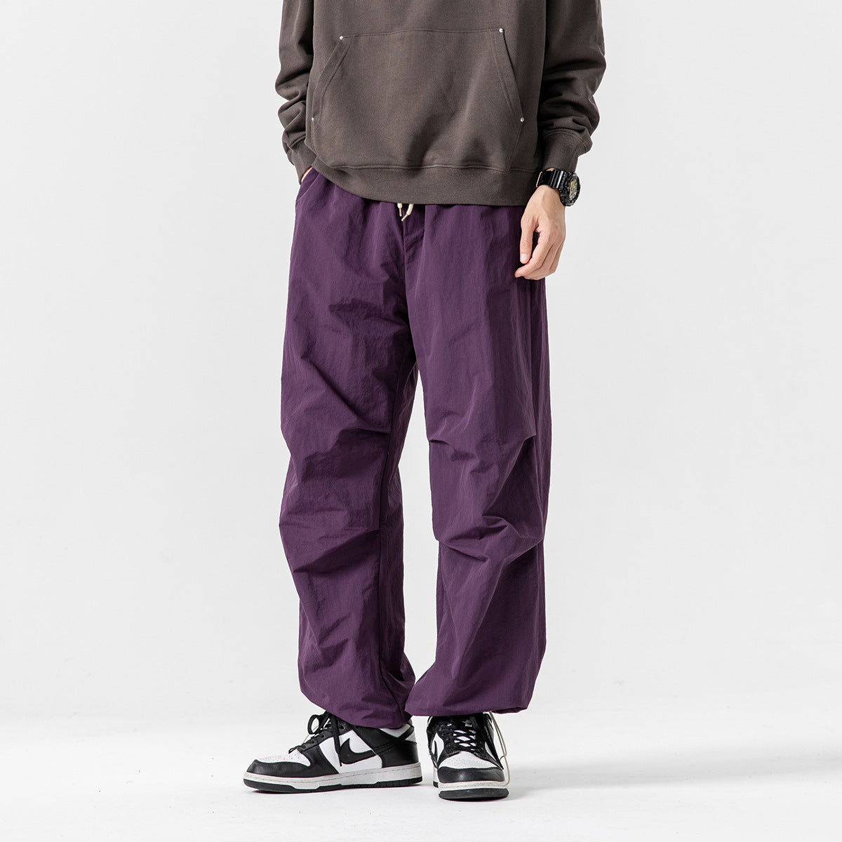 Model wearing loose purple drawstring pants with a relaxed fit and gathered hems.