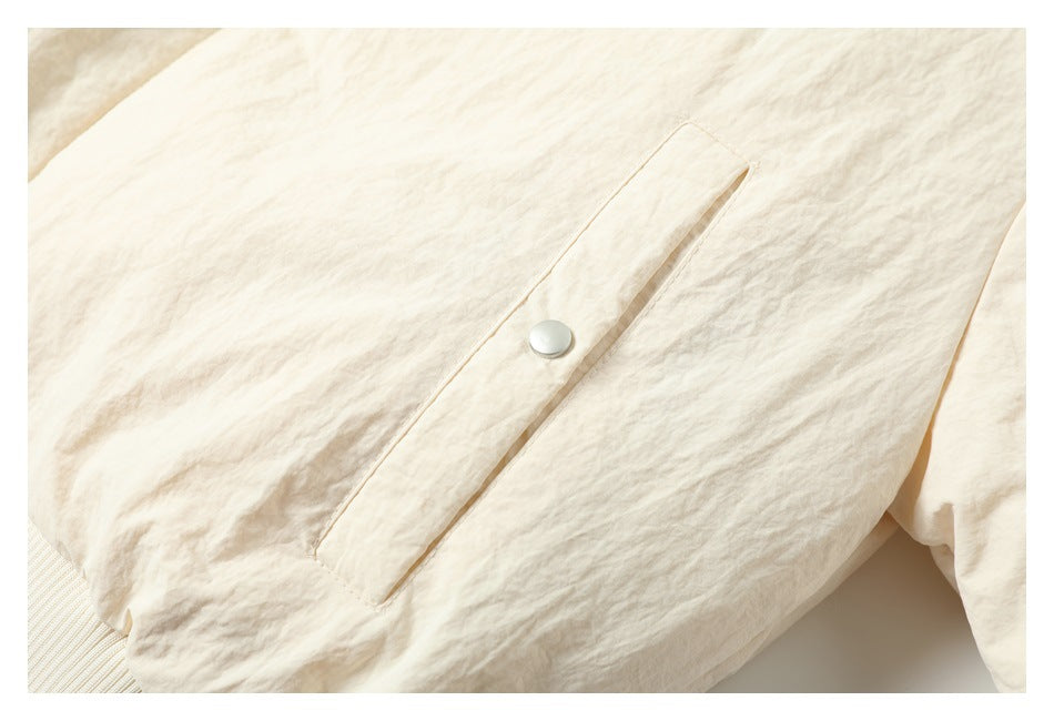 Close-up of a cream garment flap with a single round snap button and stitched edges.