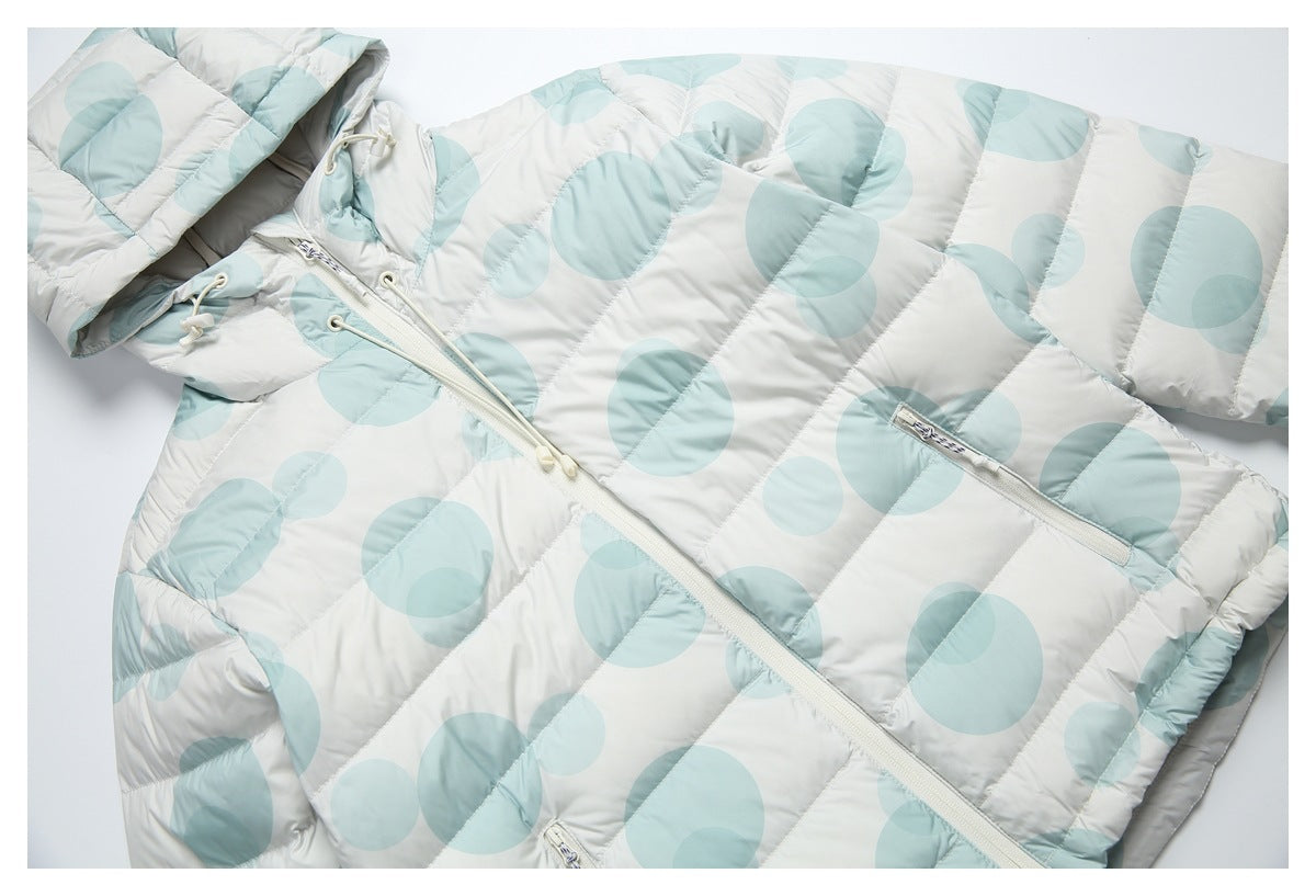 Close view of the white and pale aqua circle-print puffer jacket, showing its hood, front zipper and zip pockets.