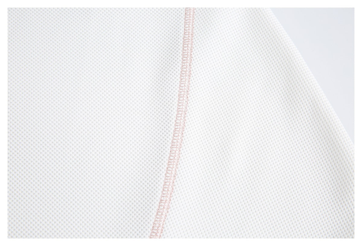 Close-up of ivory textured knit fabric with a narrow pale pink overlocked seam.