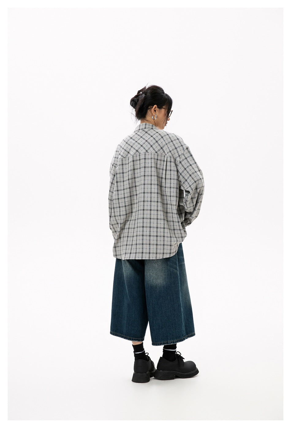 Rear three-quarter view of a model wearing the gray plaid blouse, showing its gathered back yoke and loose fit.