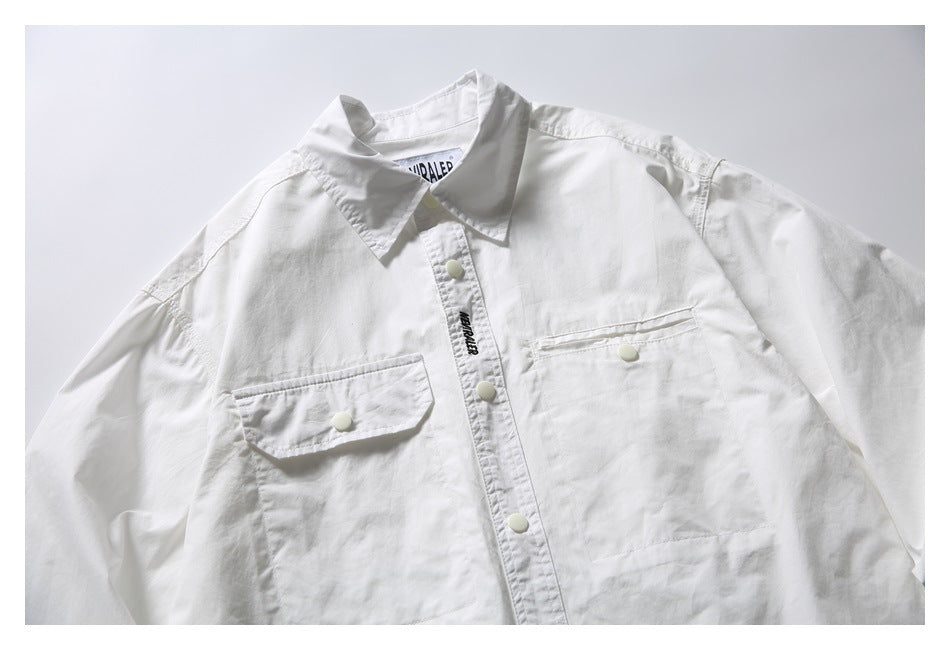 White long-sleeve button-up shirt with pointed collar, two chest pockets and snap buttons, shown from the front.