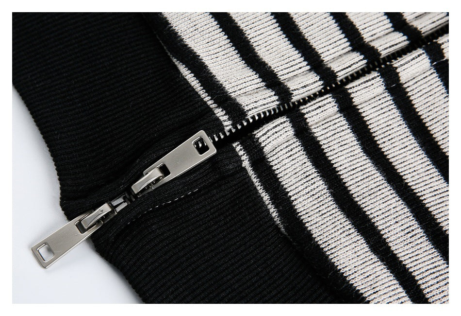 Close-up of a silver zipper joining black ribbed trim and black-and-white striped knit fabric.