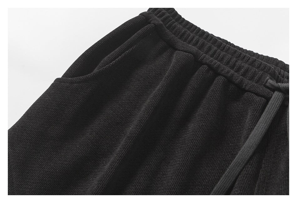 Close-up of black pants showing a side pocket, gathered waistband, and drawstring.