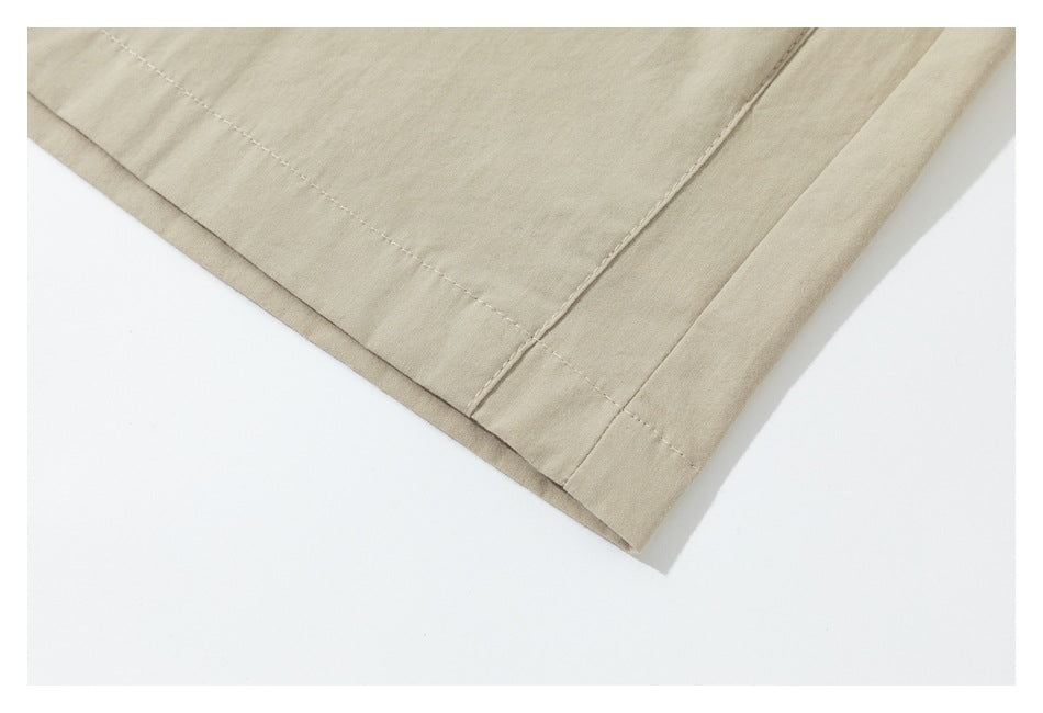 Close-up of the beige garment's double-stitched hem and overlapping fabric layers.