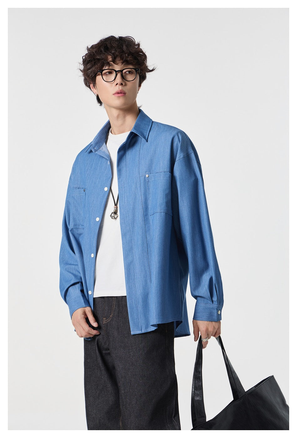 Closer view of a model wearing an oversized blue button-front shirt with chest pockets over a white T-shirt.