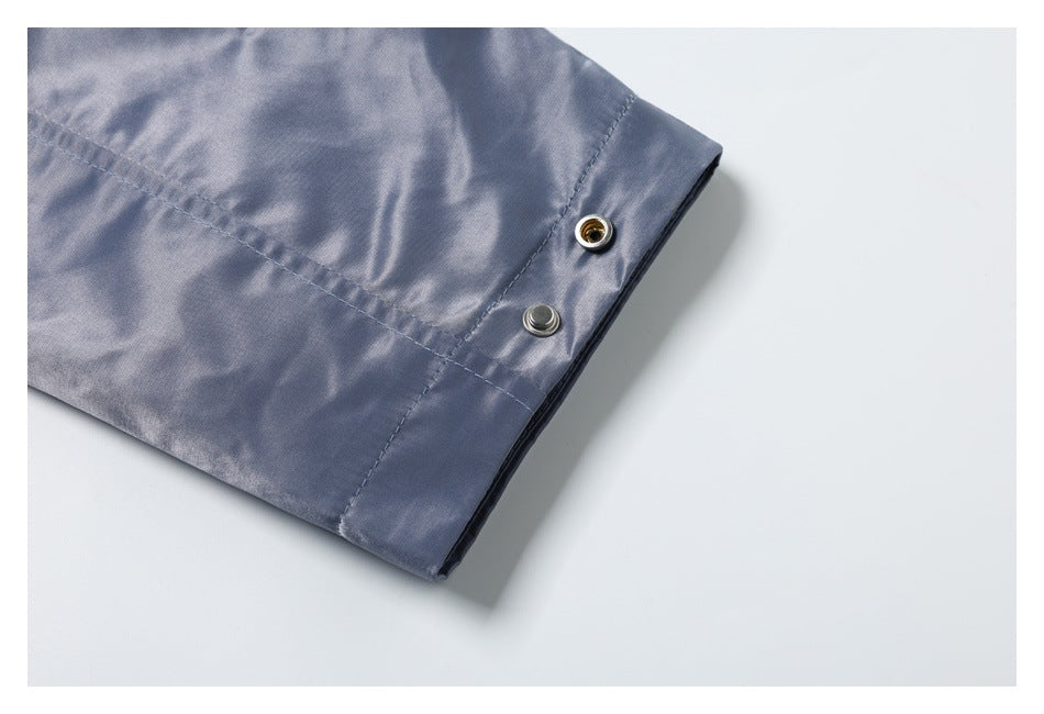 Close-up of a blue-gray garment cuff with two metal snap fasteners and visible stitching.