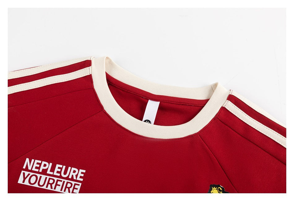 Close-up of the red jersey neckline with a cream ribbed collar, cream shoulder stripes, and partial white chest lettering.