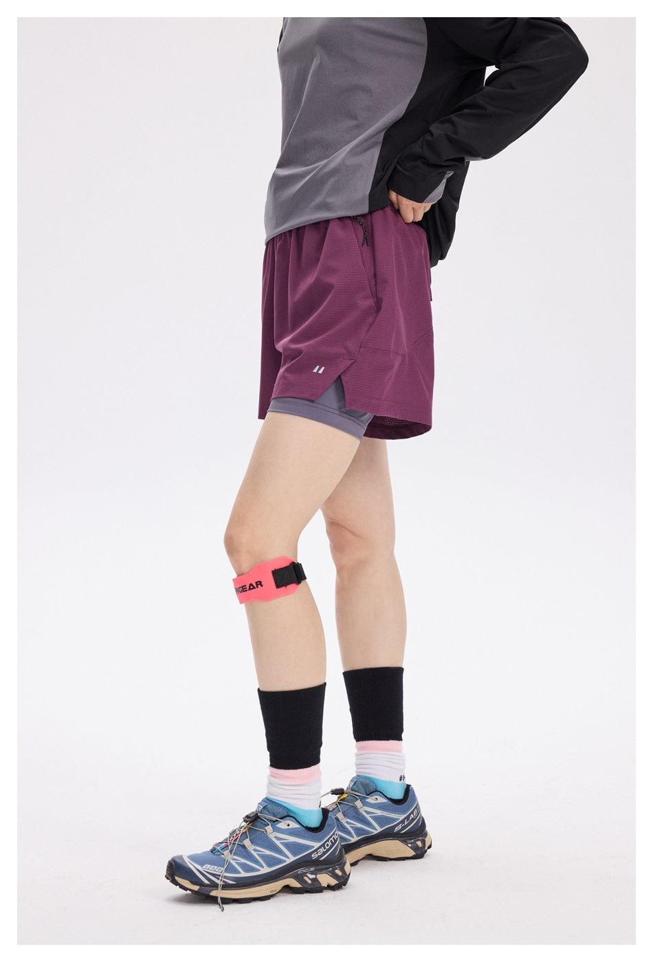 Side view of a model wearing burgundy running shorts over gray compression shorts.