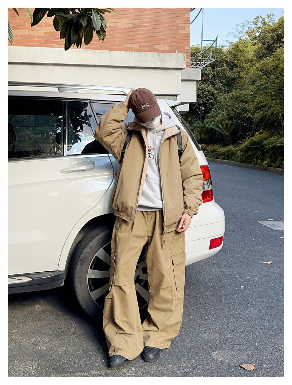 Person wearing a tan jacket with cream sherpa lining and loose tan cargo pants beside a car.