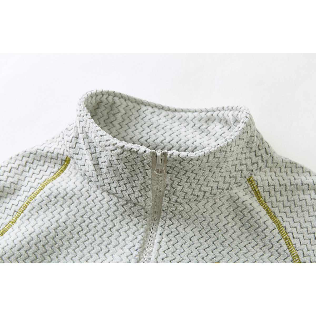 Close-up of a cream and gray zigzag-patterned top with a stand collar, short front zipper, and mustard seam accents.