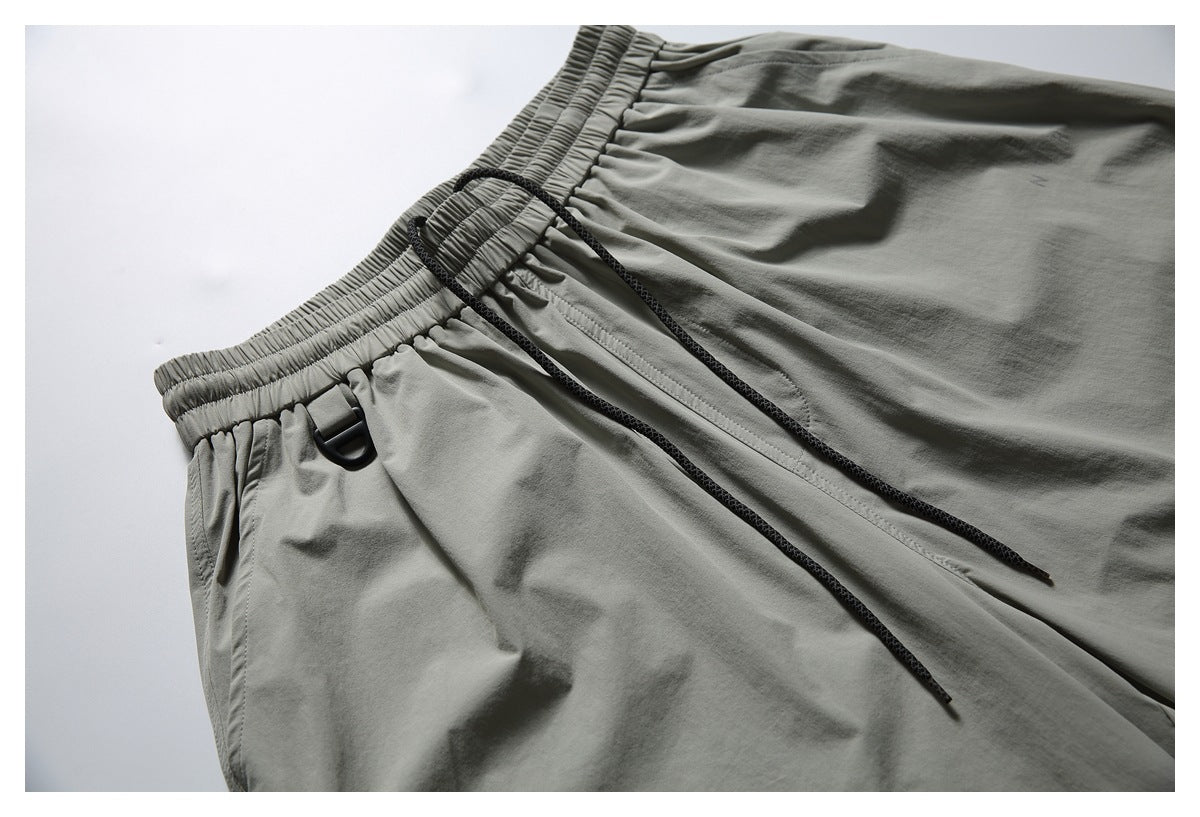 Gray pants waistband with a black drawcord and a small black loop detail.