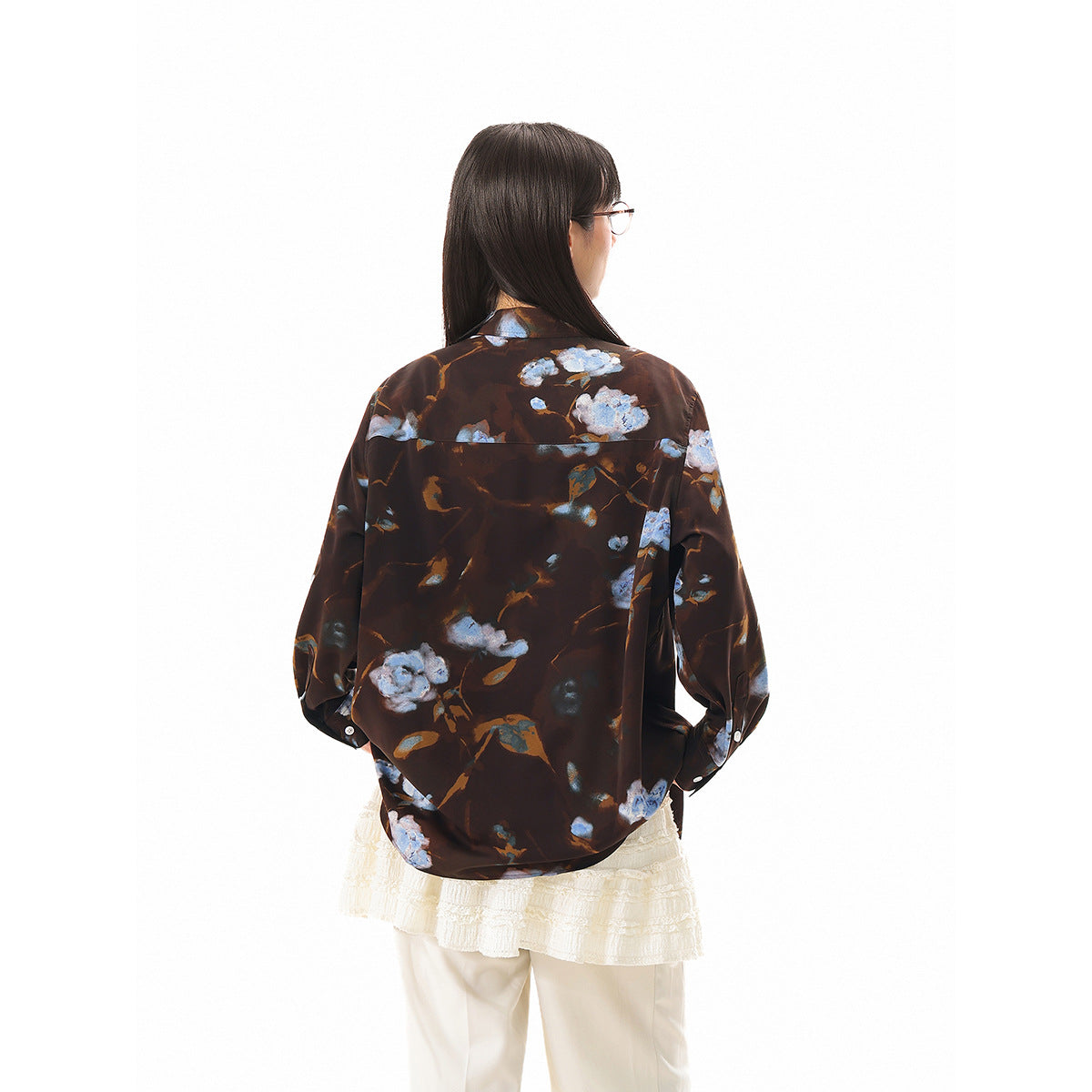 Back view of a model wearing an oversized dark brown shirt with blue and pale floral print.