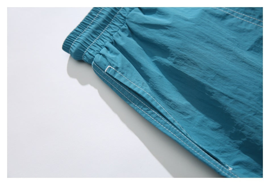 Close-up of a side pocket and contrast stitching on turquoise shorts.