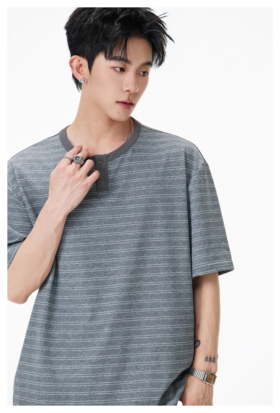 Close-up of model wearing gray striped Henley T-shirt, showing snap placket and ribbed neckline