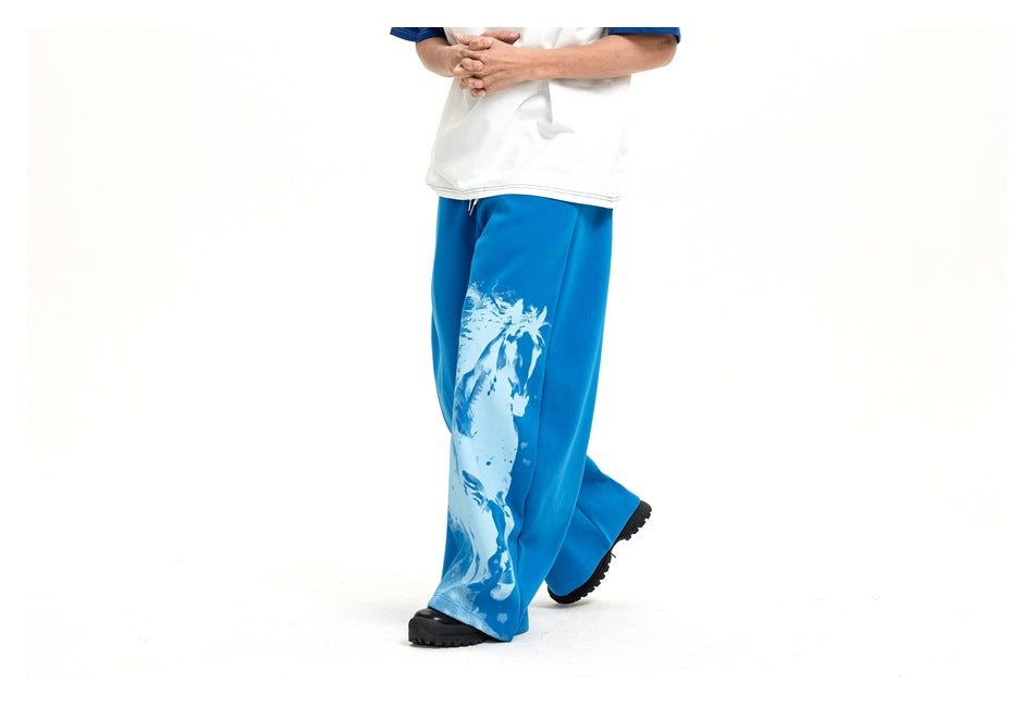 Model in bright blue wide-leg pants with a large white horse graphic, shown at an angled front view.