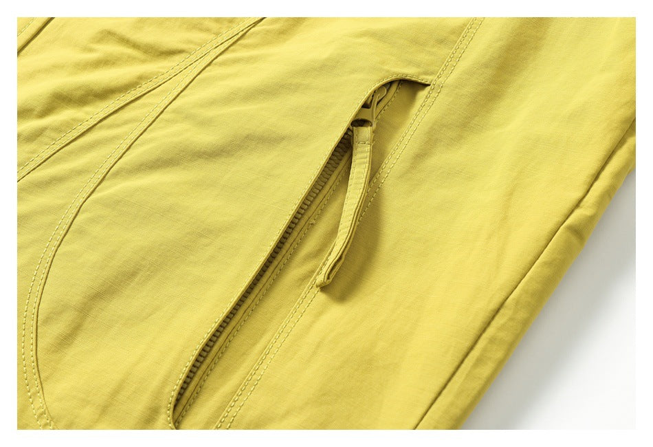 Close-up of a slanted zippered pocket on the mustard-yellow jacket.