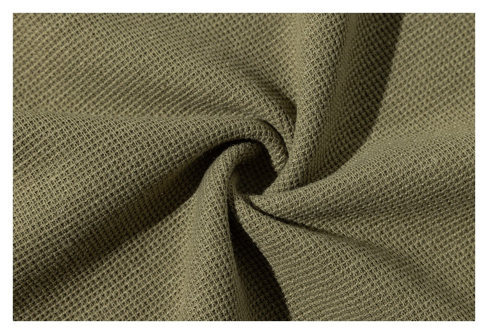 Close-up of olive-khaki textured fabric gathered into a twist, showing its waffle-like weave.