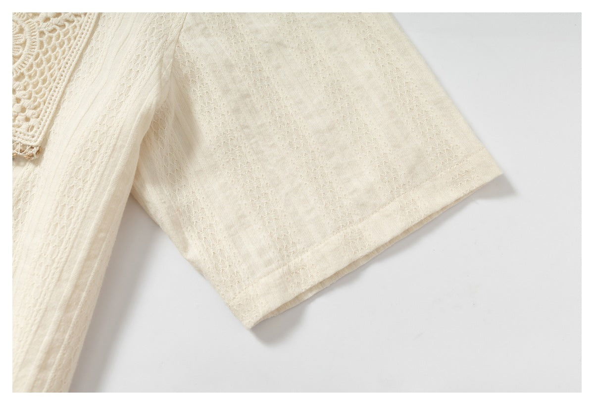 Close-up of an ivory sleeve hem with subtle woven texture and a crocheted trim visible at the edge.