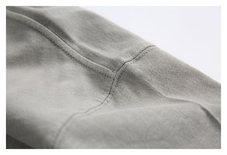 Close-up of a light gray garment showing a ribbed cuff joined to the sleeve with visible seams.