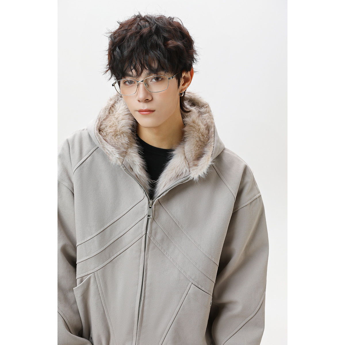 Close-up of a model wearing a taupe-gray zip-front hooded jacket with pale faux-fur lining and diagonal panel seams.