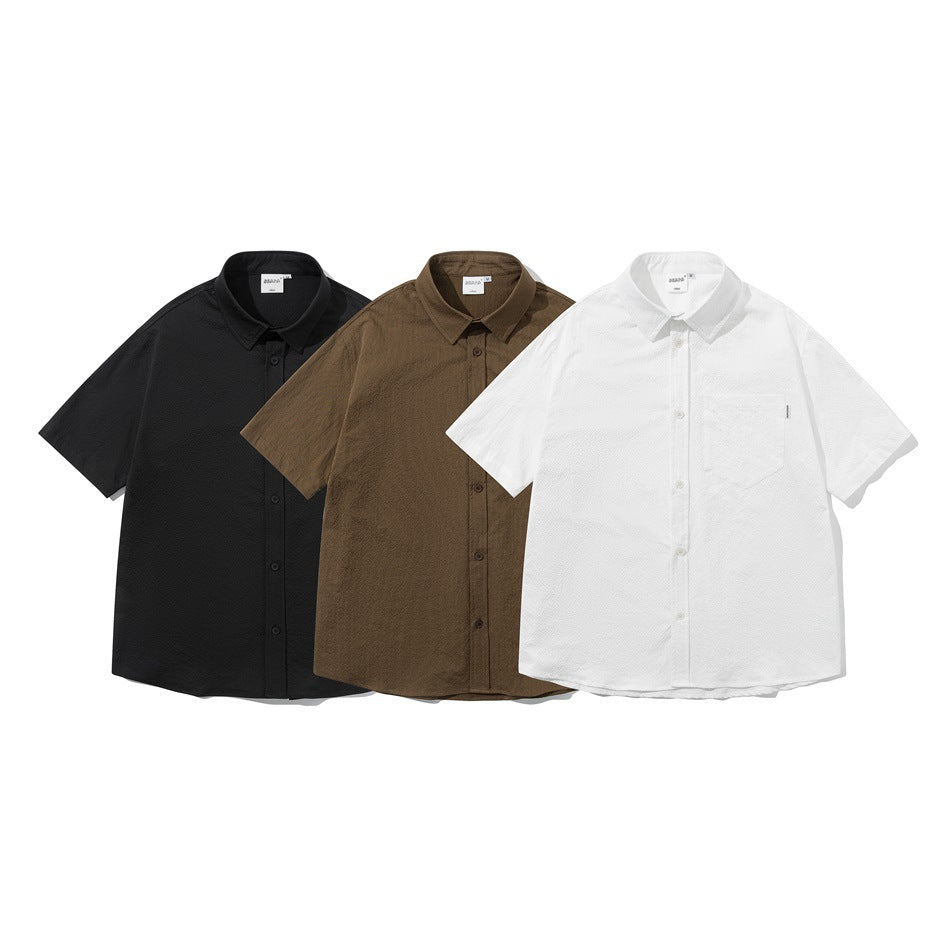 Three short-sleeve button-up shirts laid out front-facing in black, brown and white.