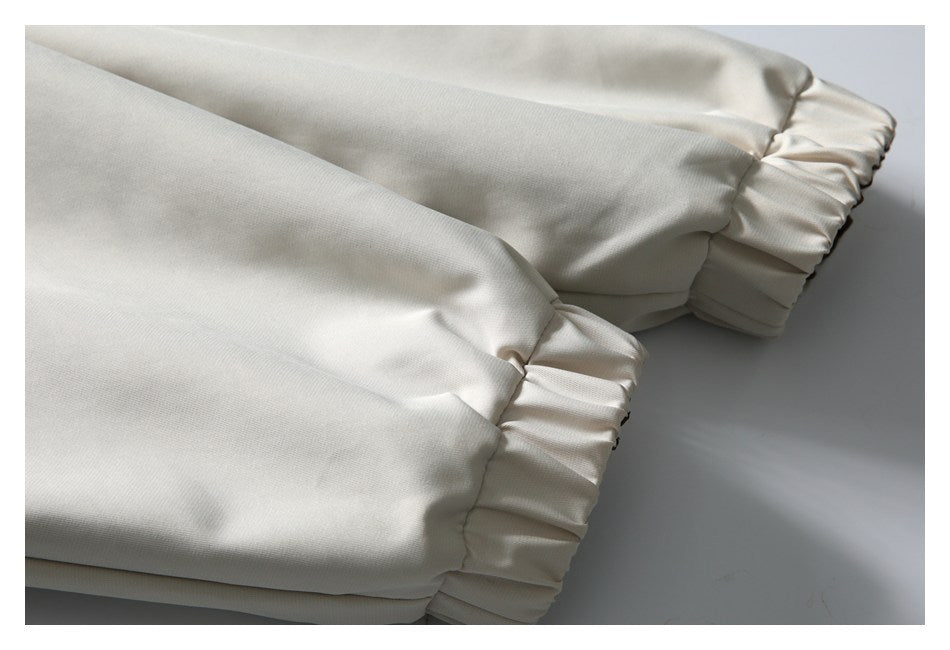 Close-up of ivory fabric gathered into elastic cuffs at two sleeve ends.
