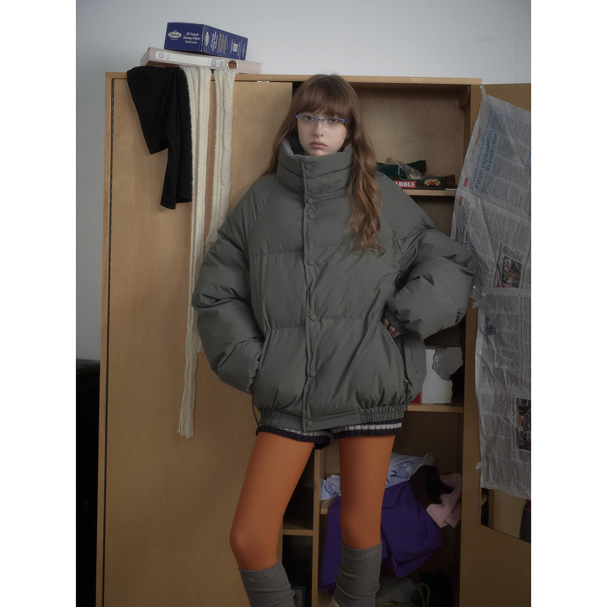 Model wearing an oversized charcoal-gray puffer jacket with a high snap-button collar and voluminous sleeves.
