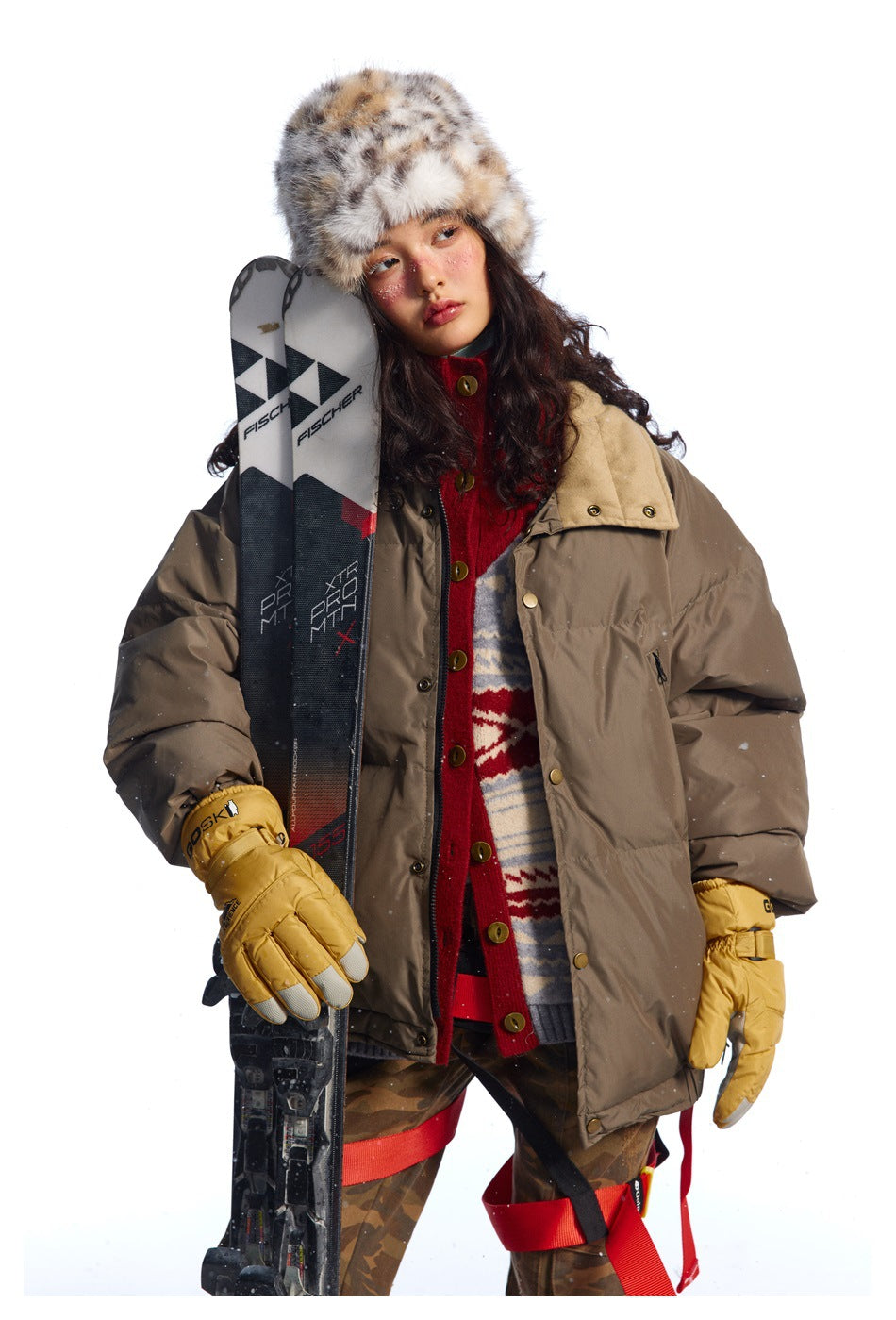 Model wearing an oversized taupe padded jacket with a contrasting tan collar, layered over a red patterned knit.