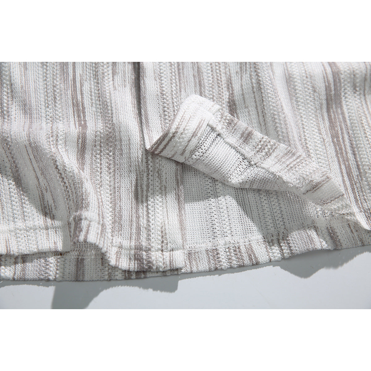 Close-up of a folded shirt edge showing the open-knit underside and striped fabric.