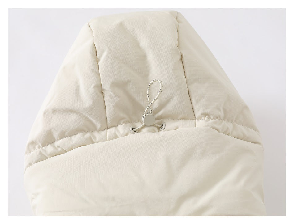 Close-up of an ivory padded hood with a cord-and-toggle adjuster against a light background.