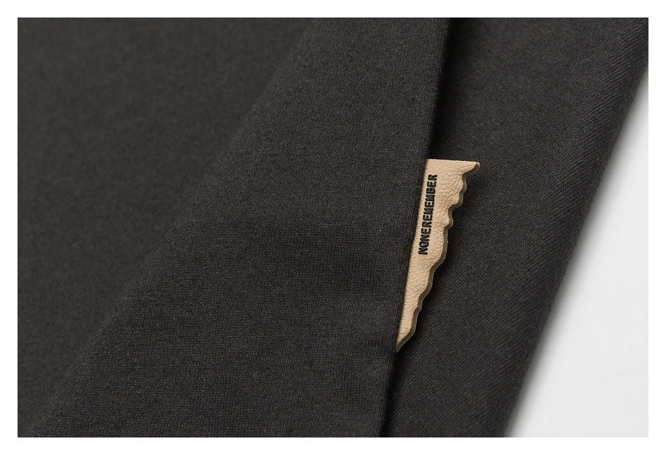 Close-up of a small beige branded tag attached to black fabric.