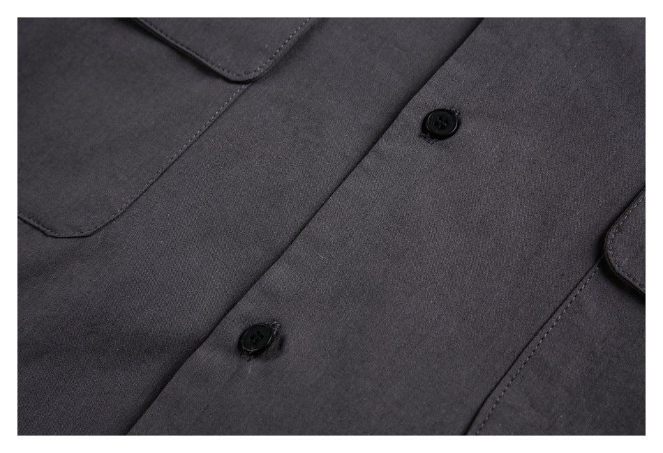 Close-up of a charcoal button-front garment with black buttons and part of a pocket.