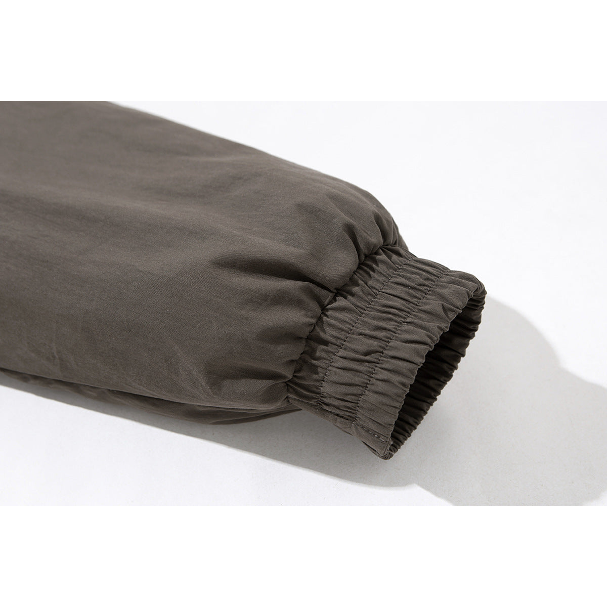 Close-up of a charcoal gray jacket sleeve ending in a gathered elastic cuff.