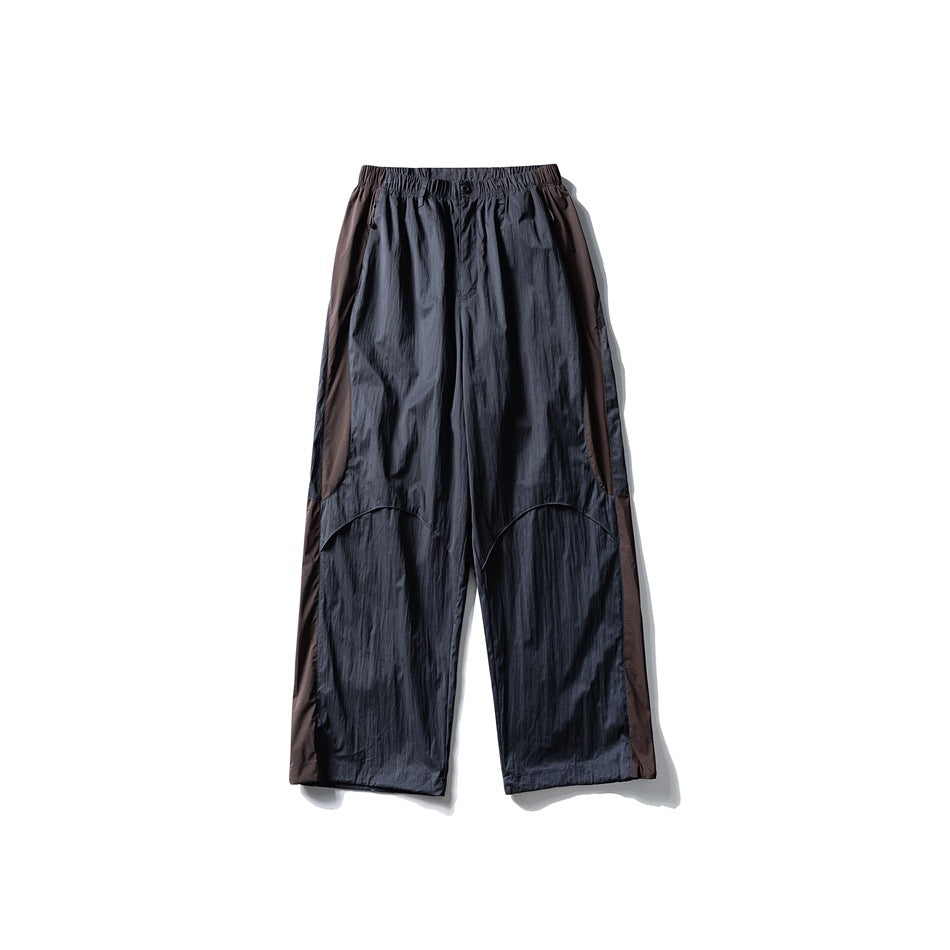Dark slate gray wide-leg pants with brown side panels, elastic waist and curved knee seams, flat lay front view