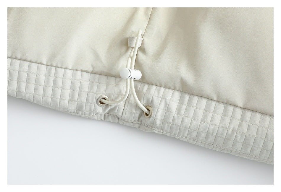 Close-up of an off-white garment hem with a quilted band, metal eyelets, and an adjustable drawcord toggle.