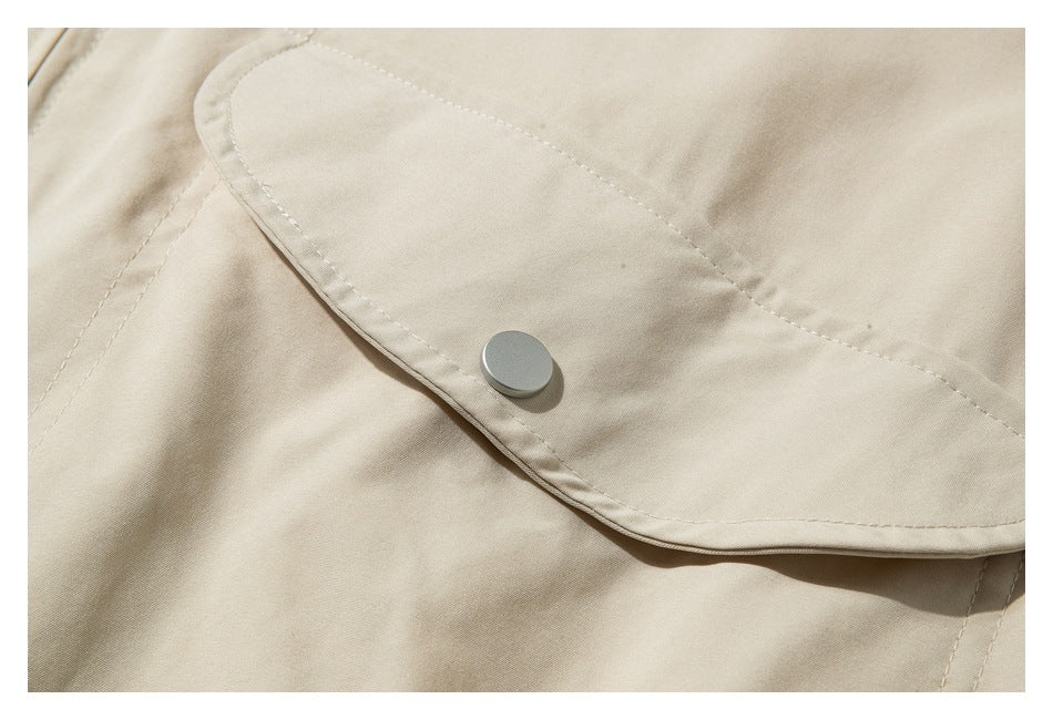 Close-up of a beige flap pocket secured with a round silver snap.