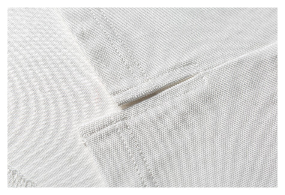 Close-up of white garment fabric with a stitched seam and folded edge.