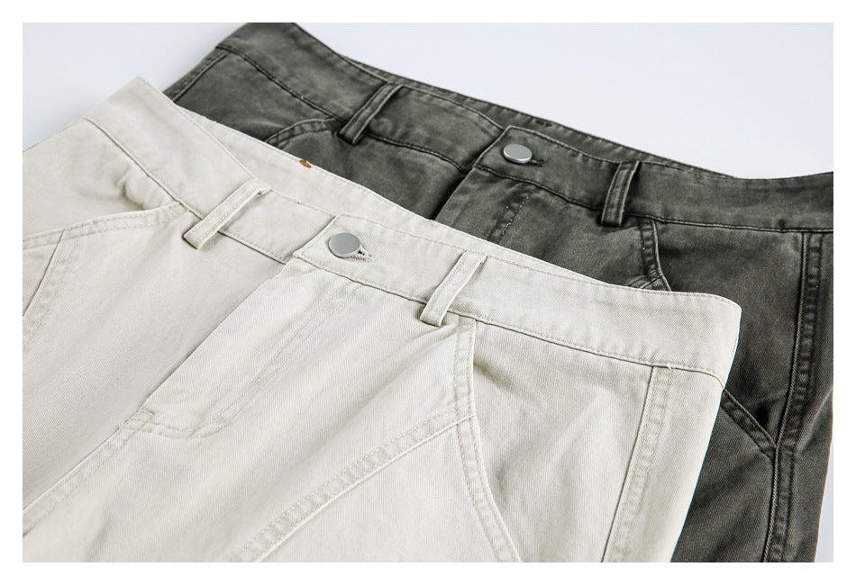Close-up of ivory and charcoal pants waistbands, showing belt loops, buttons and curved front seams.